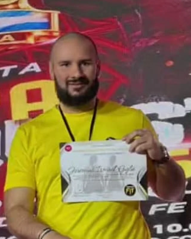 Jeremías Giglio sonriendo, con remera amarilla y un diploma en la mano